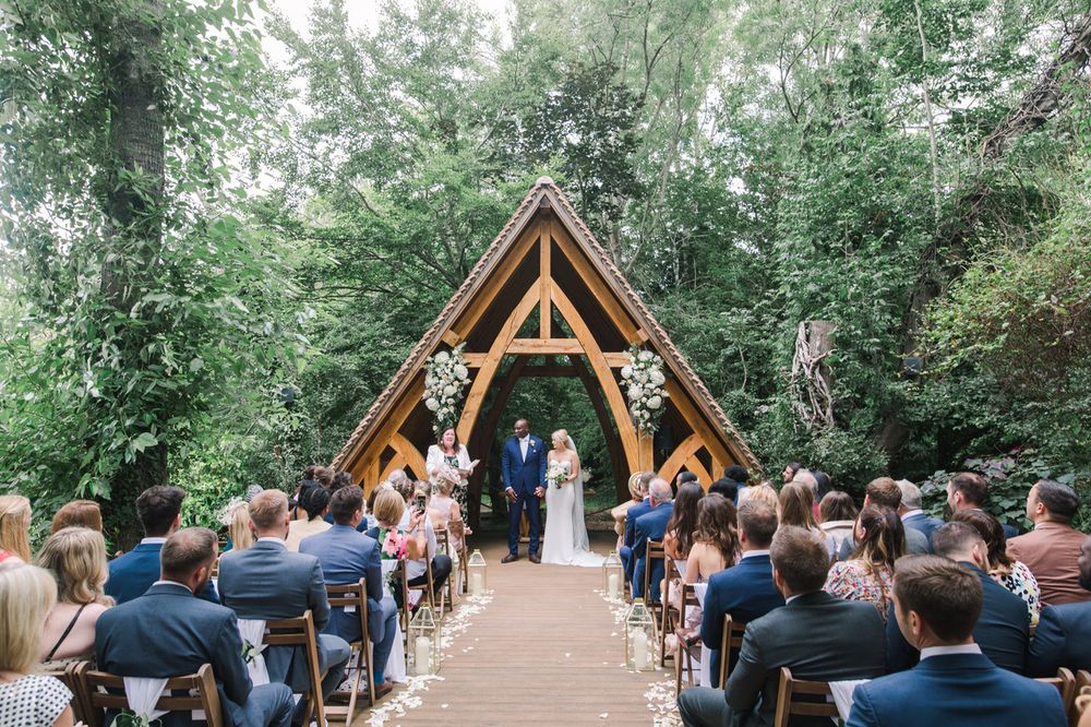 Wooden chapel structure in a forest setting with wedding guests seated for ceremony.