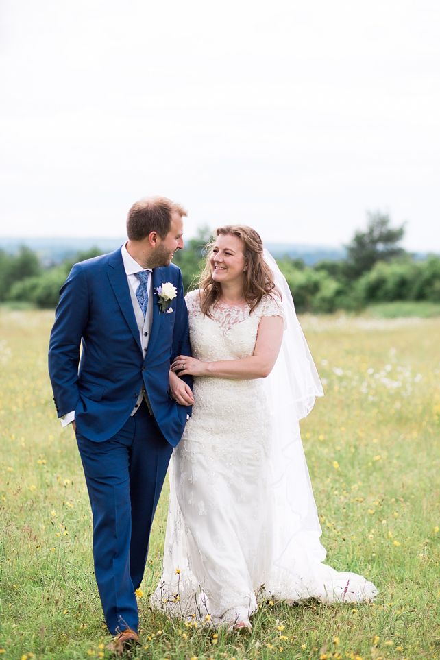 Wedding couple shares joyful moments together in sunny wildflower meadow.