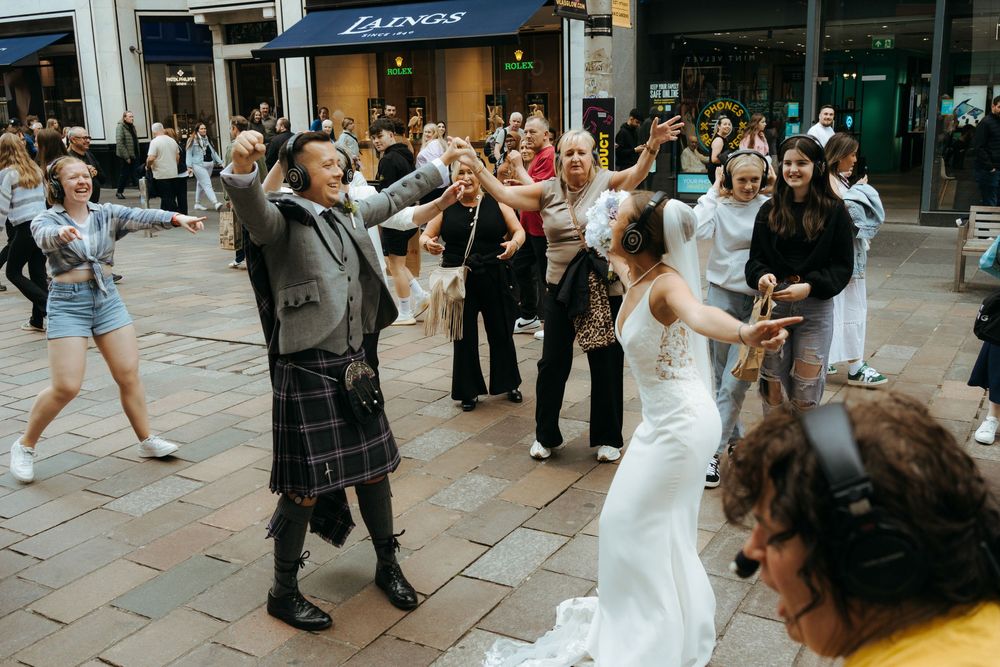 People dancing and celebrating together on a pedestrian street in an urban setting.