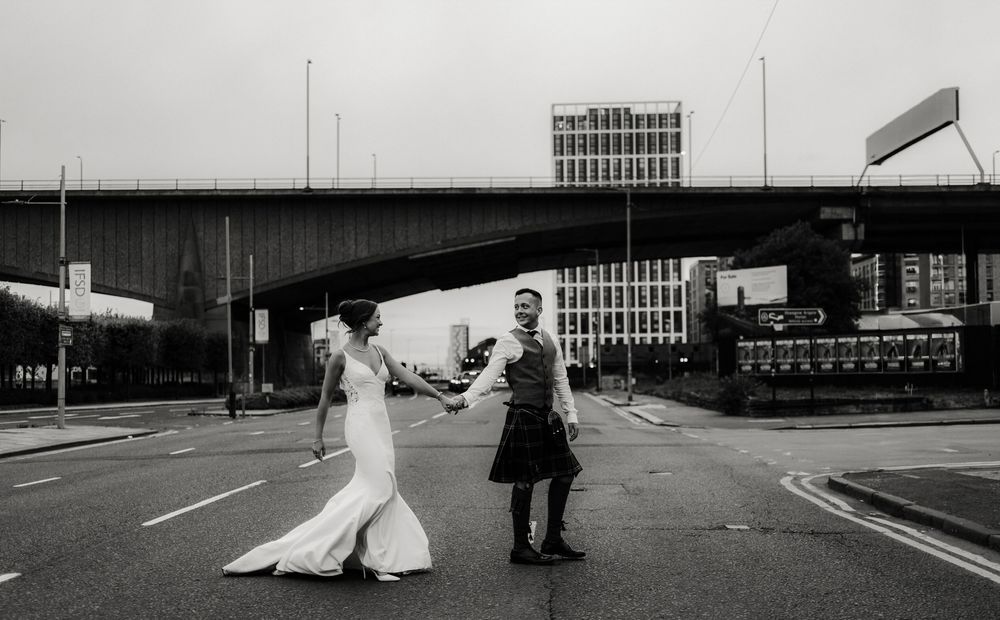 Black and white urban street scene with figures walking along a wide empty road.