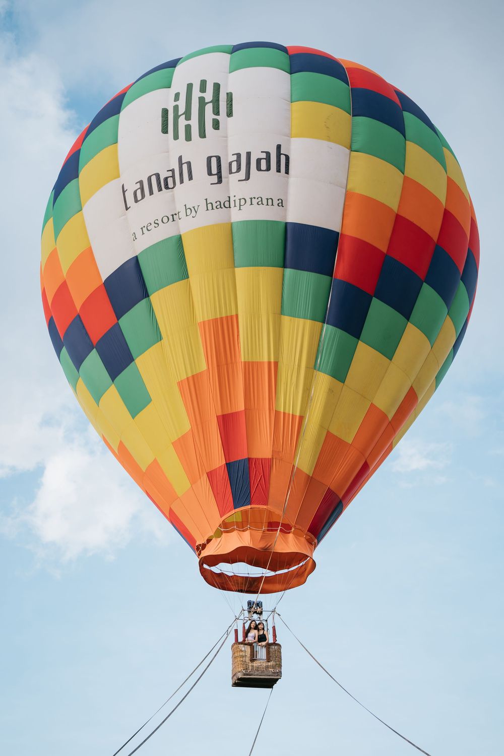 Vibrant patterned hot air balloon with geometric design floating in clear blue sky.