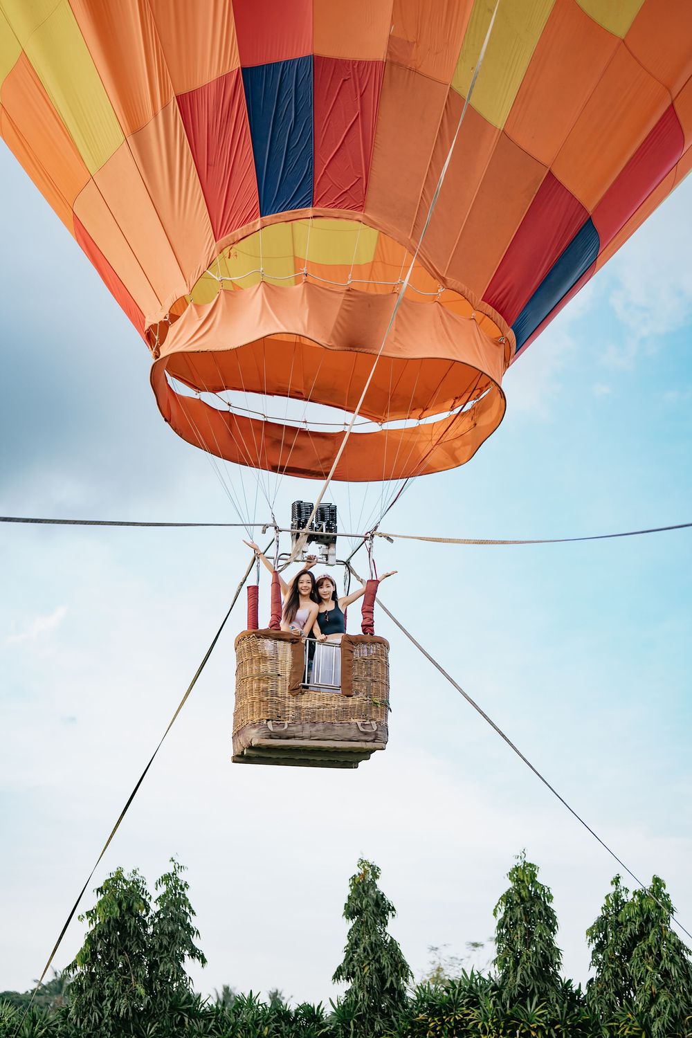 Colorful hot air balloon with orange and yellow panels ascending against blue sky.