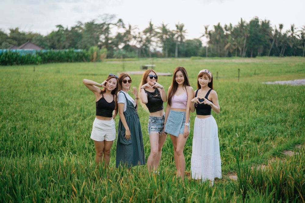 Group enjoying a sunny day in grassy field with palm trees in background.