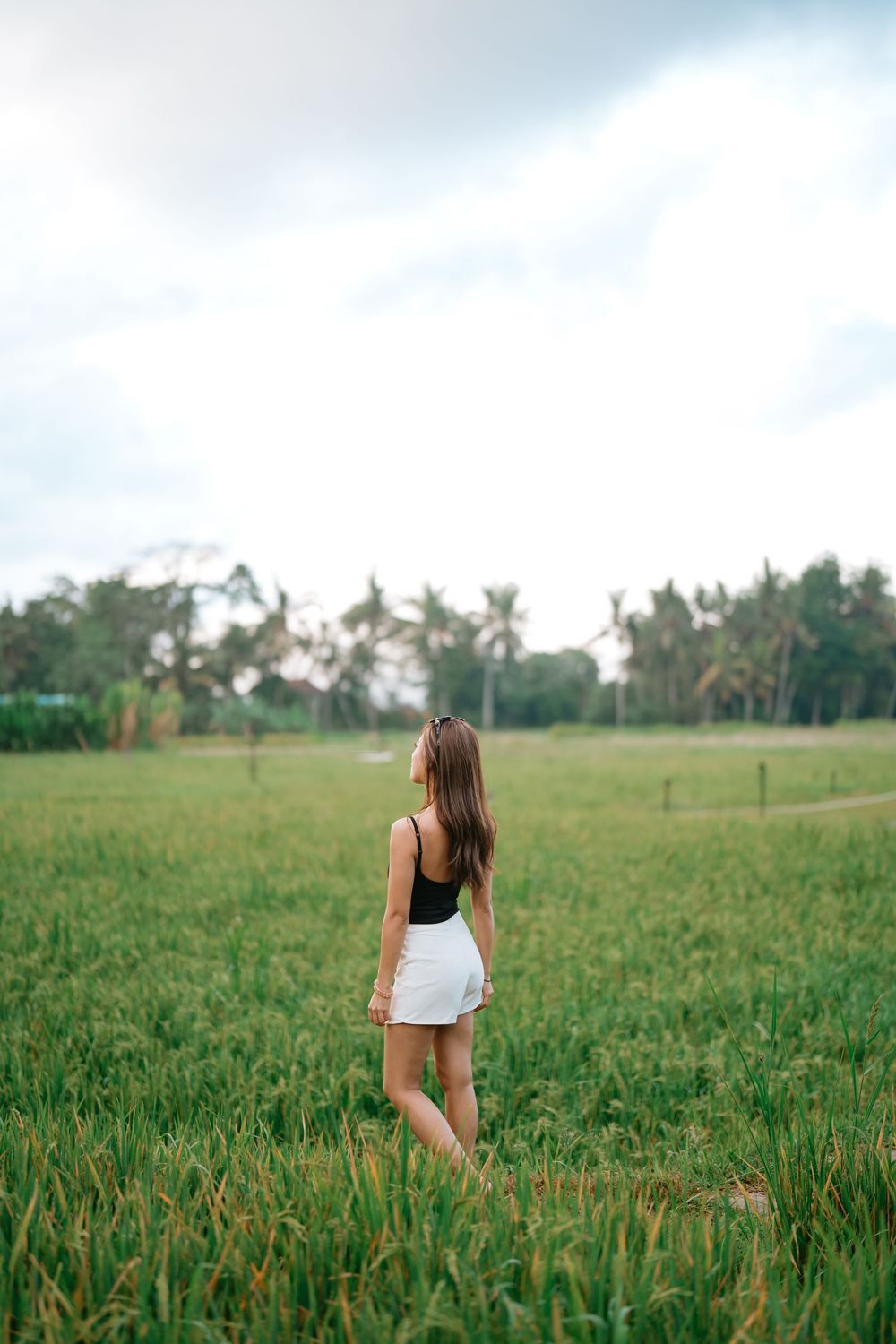 A figure walks through a lush green field under a bright summer sky.