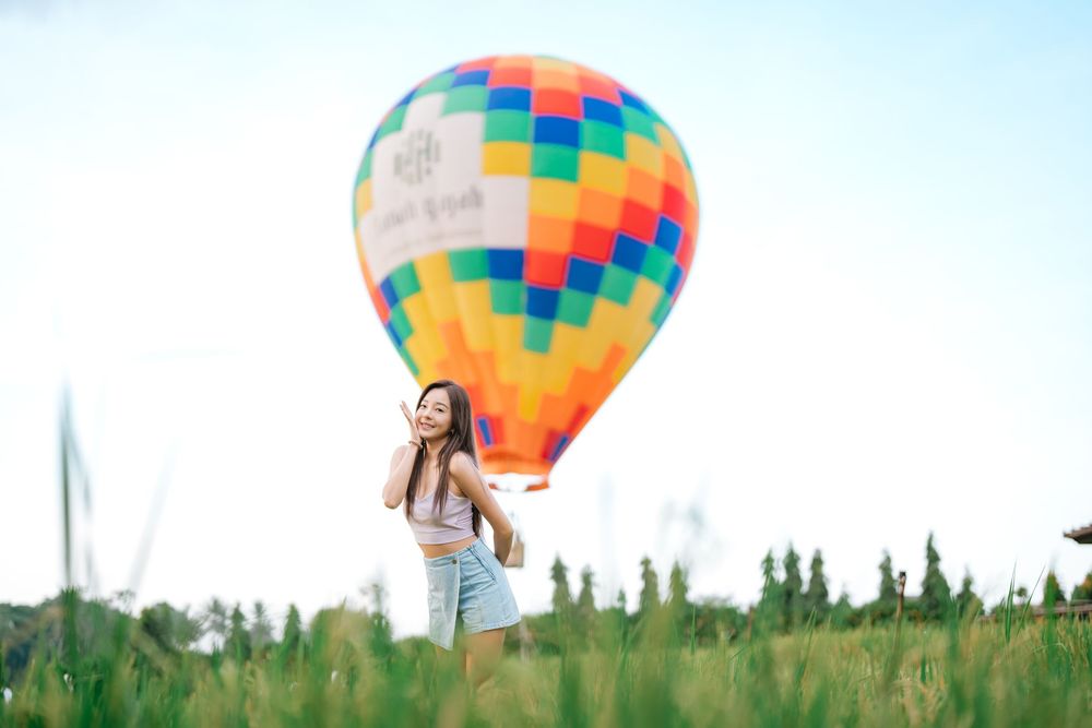 Vibrant patchwork hot air balloon hovering above a grassy meadow.