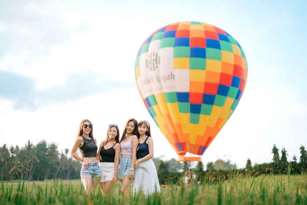 Group enjoying a summer day with a colorful hot air balloon in a green field.
