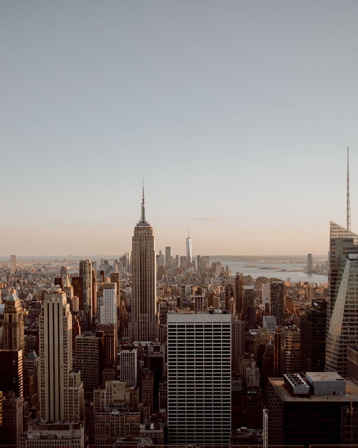 Panoramic cityscape view of Manhattan skyline at dusk with Empire State Building prominent.