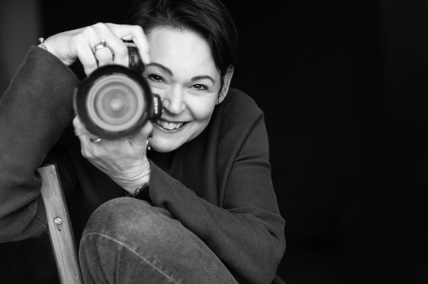 Fotografin in schwarz/weiß mit Kamera in der Hand., seitlicher Blick zur Kamera- authentisches, professionelles Portrait