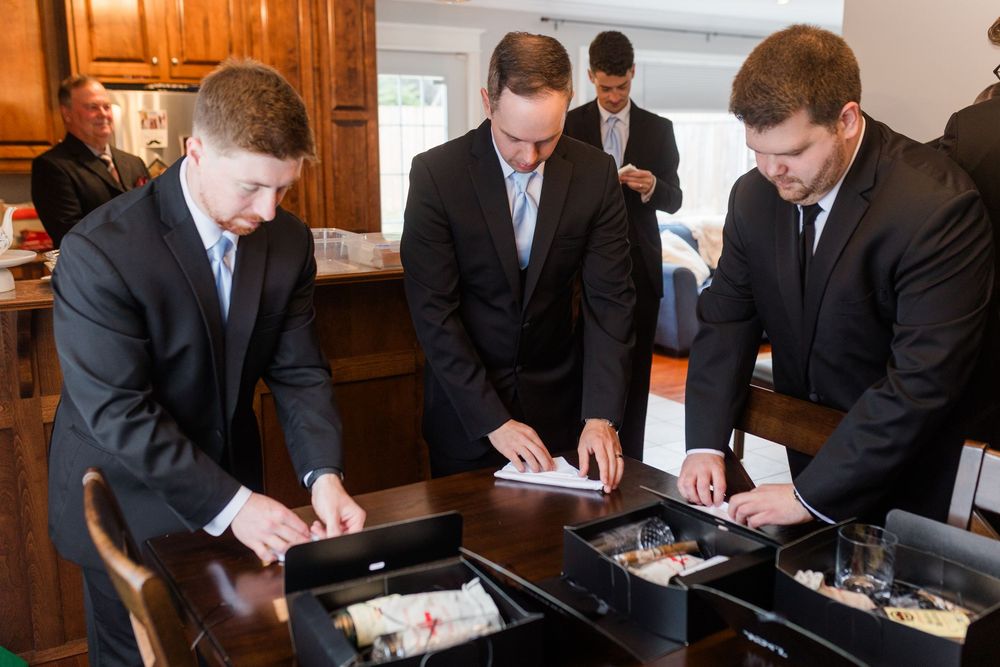 Three business professionals in dark suits reviewing documents together at a wooden desk in an office setting.