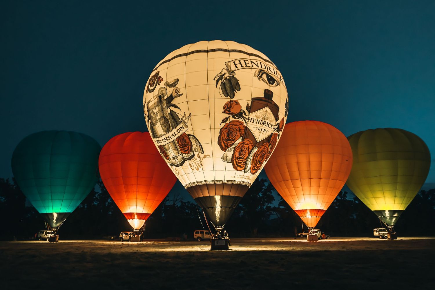 Illuminated hot air balloons glowing at night including one with world map design.
