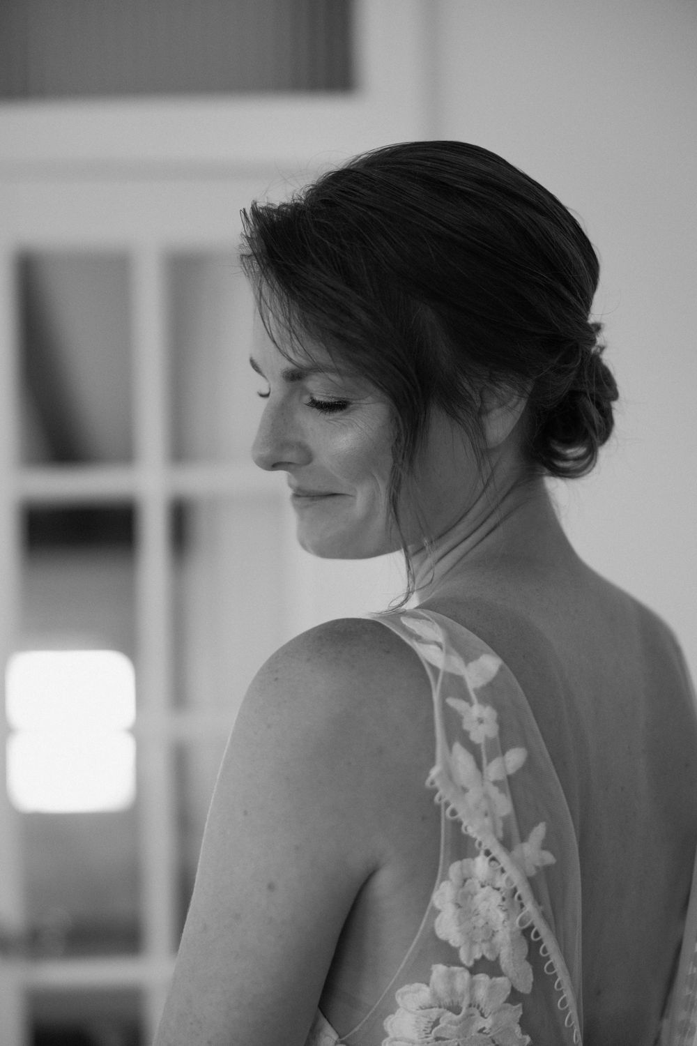 Close-up black and white photo showing intricate lace detail on back of wedding gown.