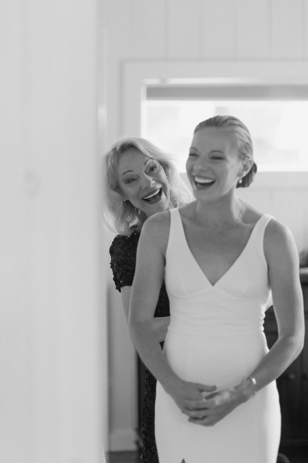 Candid moments of laughter and joy during wedding dress preparations.