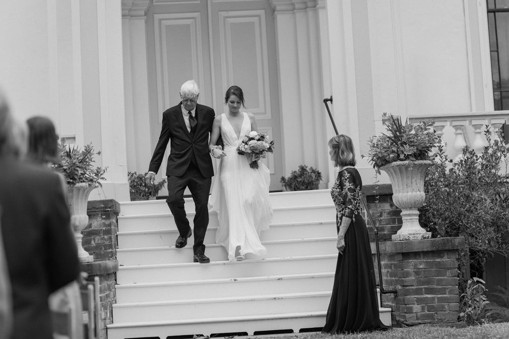 Wedding ceremony procession at an elegant white building with columns.