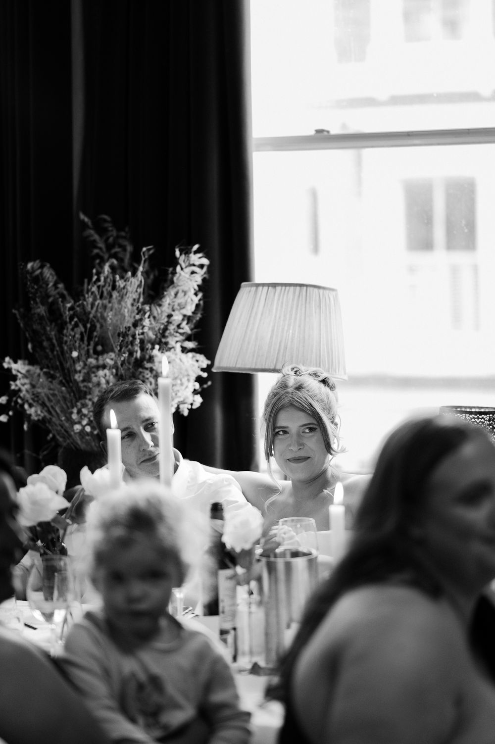 A sequence of black and white reception photos showing formal dining tables decorated with floral arrangements and lamps.