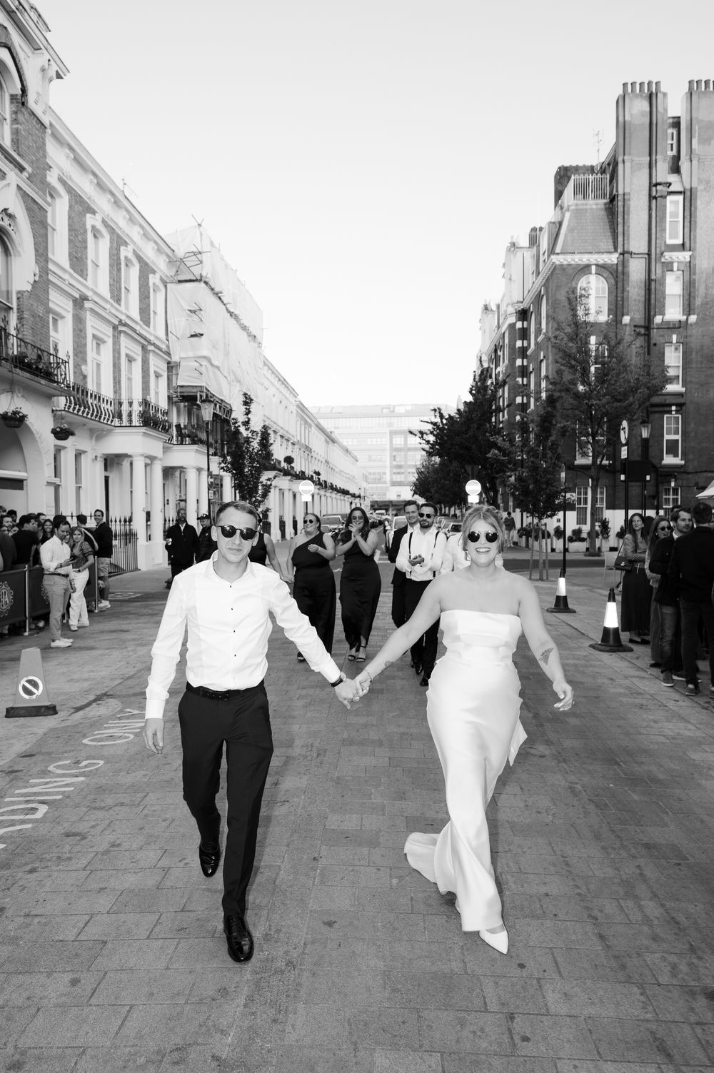 Sequence of three black and white photos showing a couple walking down a city street after their wedding ceremony.