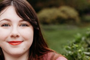 Close up portrait in outdoor setting with green foliage and natural lighting.