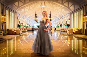 Long hallway in grand ballroom features ornate architectural details with soft lighting and reflective marble floors.