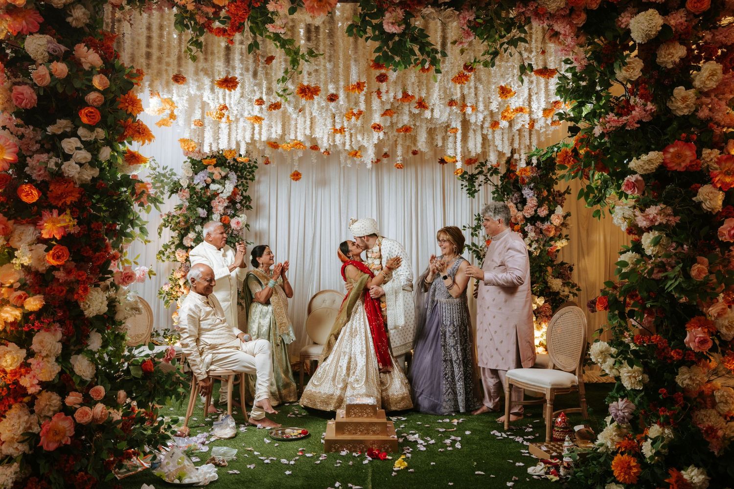A romantic outdoor wedding ceremony setup with lush floral arrangements and white decor under a dreamy garden setting.
