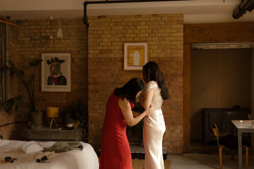 Two people practice ballroom dancing in a brick-walled studio space.