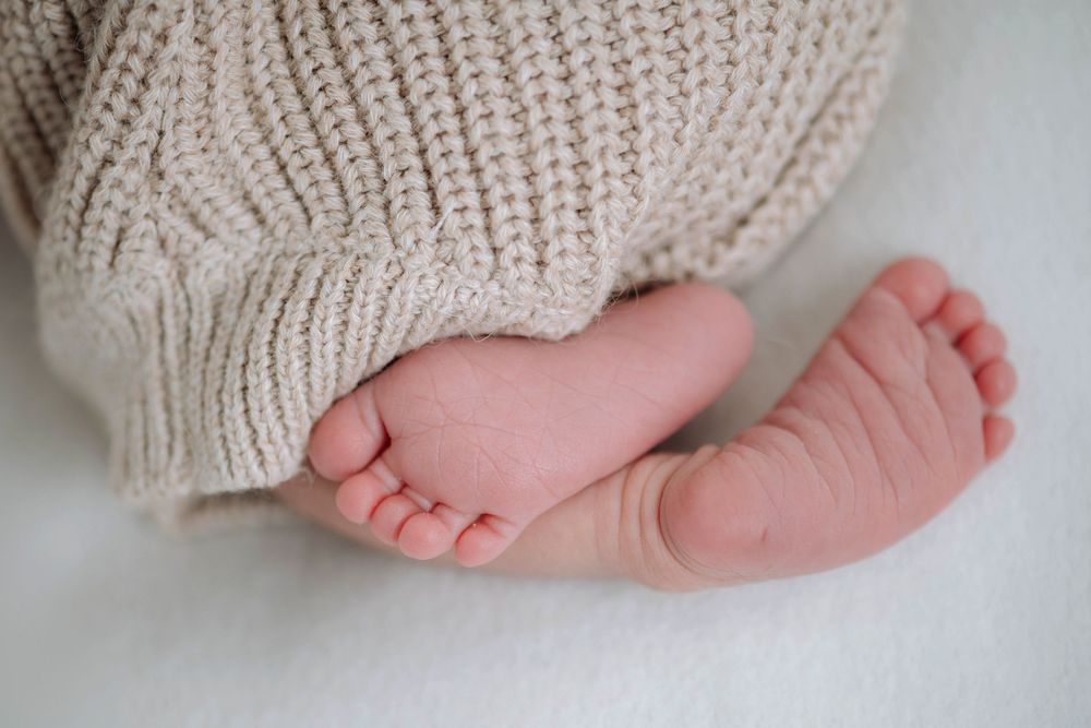 Series of photos showing tiny baby feet wrapped in a cozy beige knit blanket against a light background.