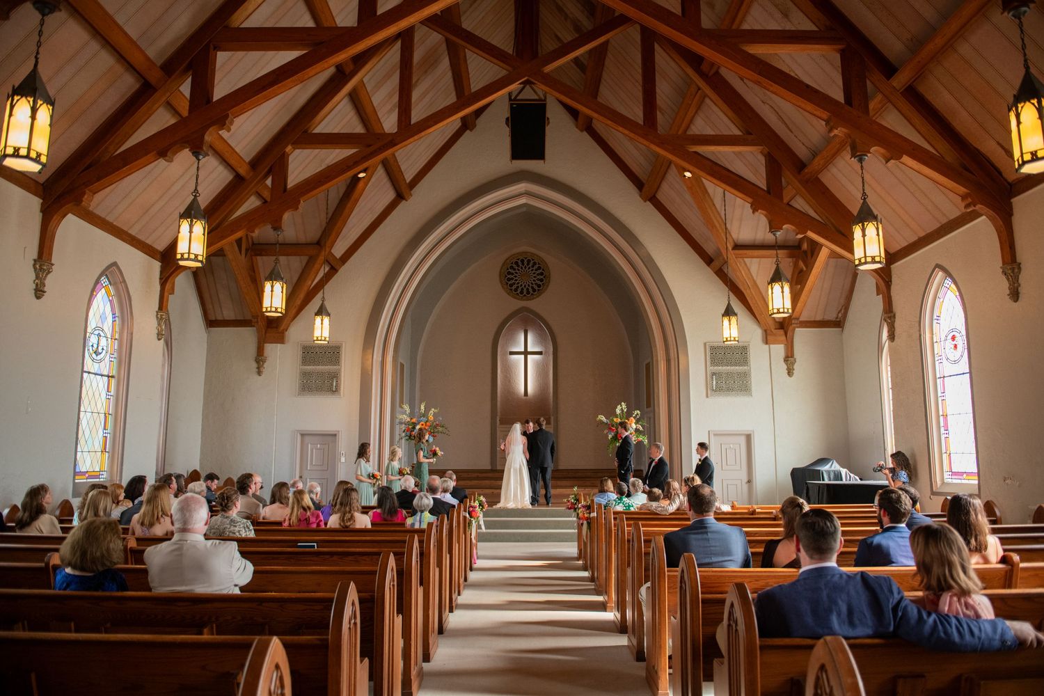 Interior shots of a traditional church wedding ceremony with vaulted ceilings and wooden beams.