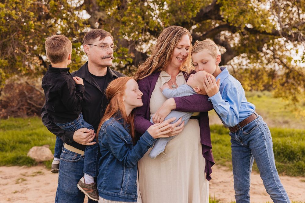 Family members embrace and play together during sunset photo session.