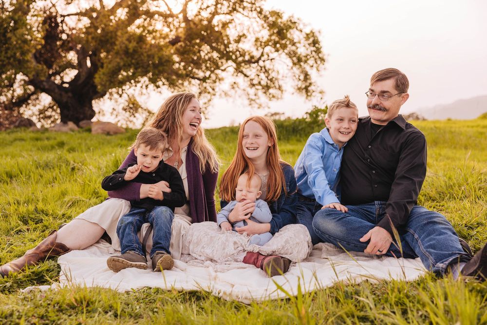 Family members share candid moments while lounging on blankets outdoors.