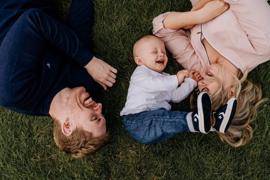 Family members lying on grass together sharing playful moments.