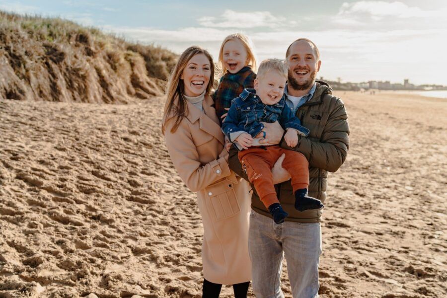Family sharing joyful moments together on a sandy beach during golden hour.