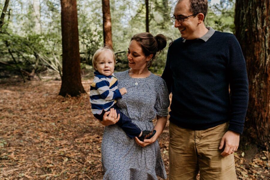 Family sharing tender moments together among tall pine trees in a forest.