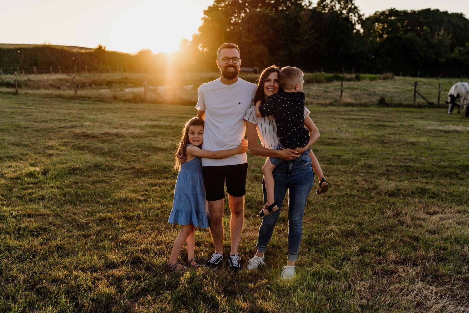 Family enjoying a sunset moment together in a grassy field during golden hour.