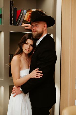 Tender embrace between a couple in formal wear against a backdrop of built-in shelving.