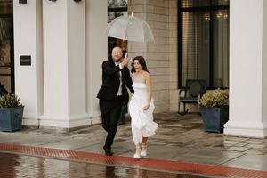 Rainy day wedding photography session outside modern building with columns.