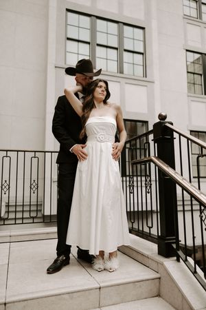 A series of intimate wedding photos captured on white stairs with industrial windows.