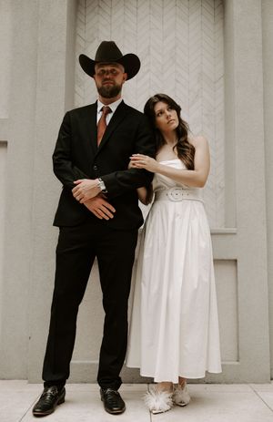 Stylish wedding couple poses in black and white against minimalist architectural backdrop.