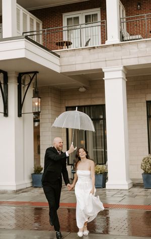 A couple shares a romantic dance under a covered walkway during a rainy wedding day.