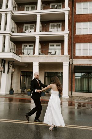 Couple performs a joyful dance sequence on wet pavement during their wedding.