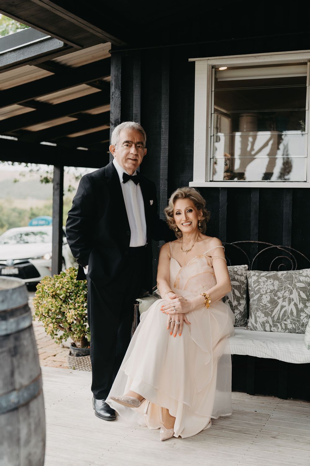 Couple sits together on stone steps in formal attire during an outdoor wedding photoshoot.