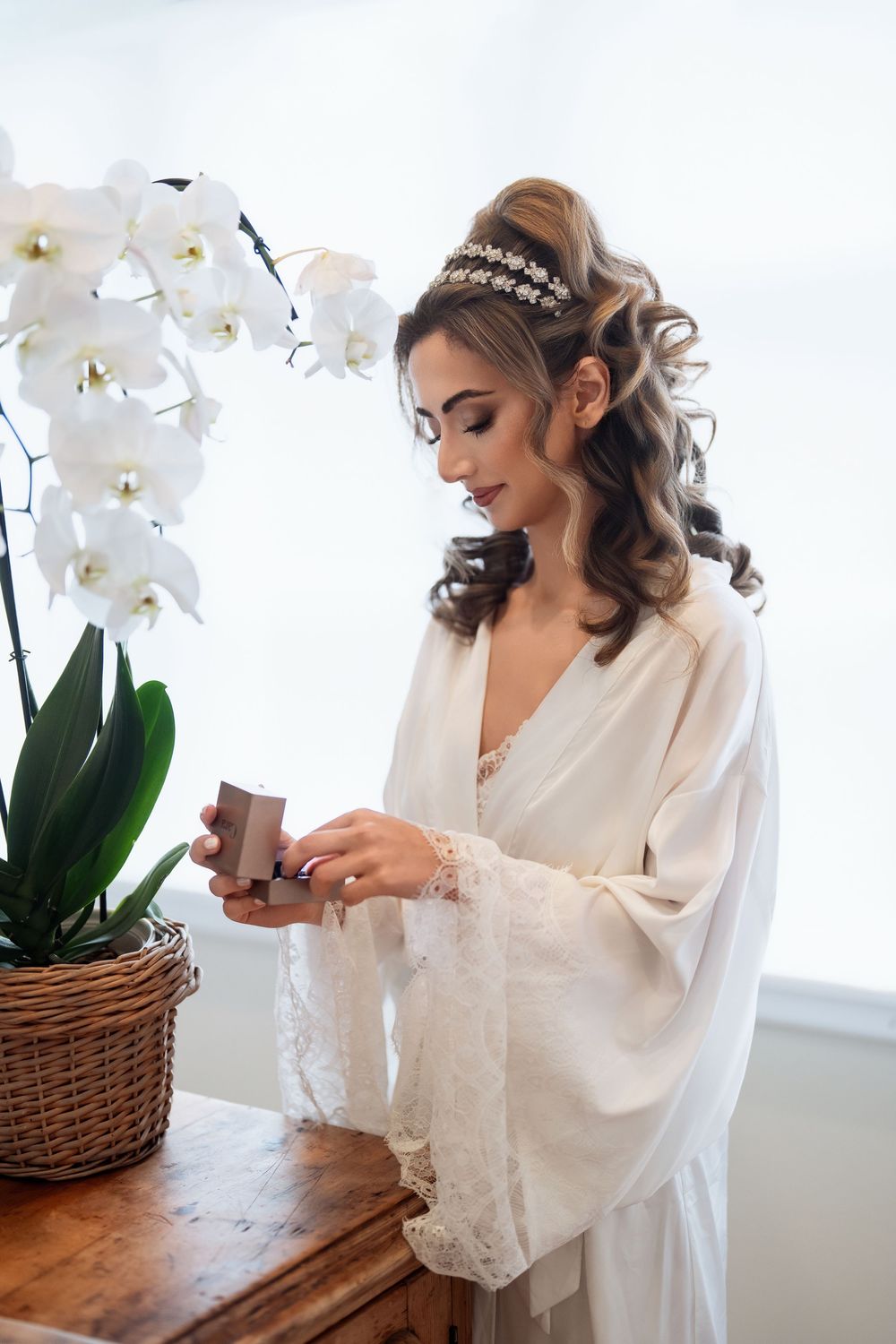 White silk robe and delicate lace trim complement the elegant orchid decor in a bright bridal getting-ready scene.