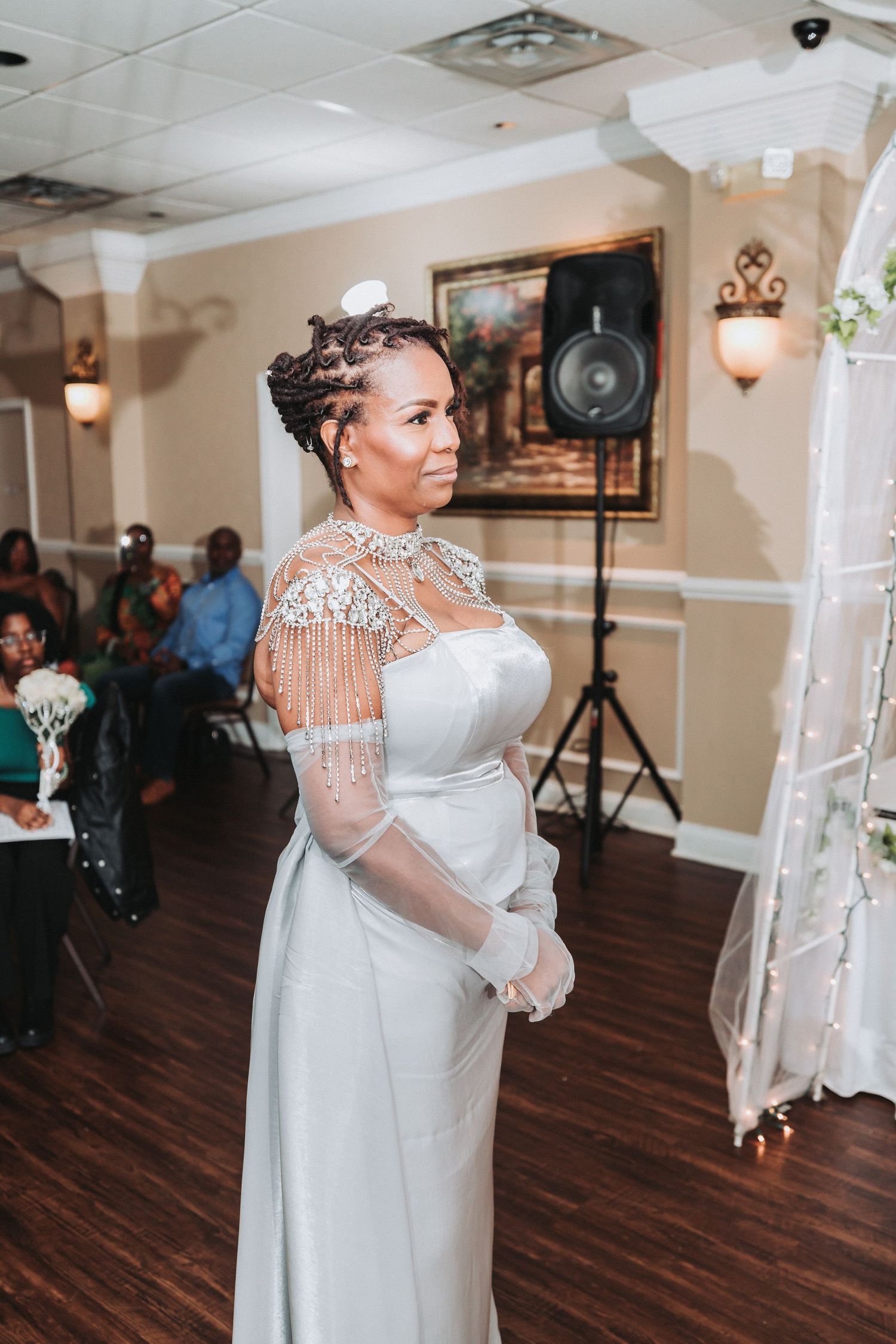 An elegant wedding reception space with hardwood floors and decorative wall sconces shows a well-appointed celebration setup.