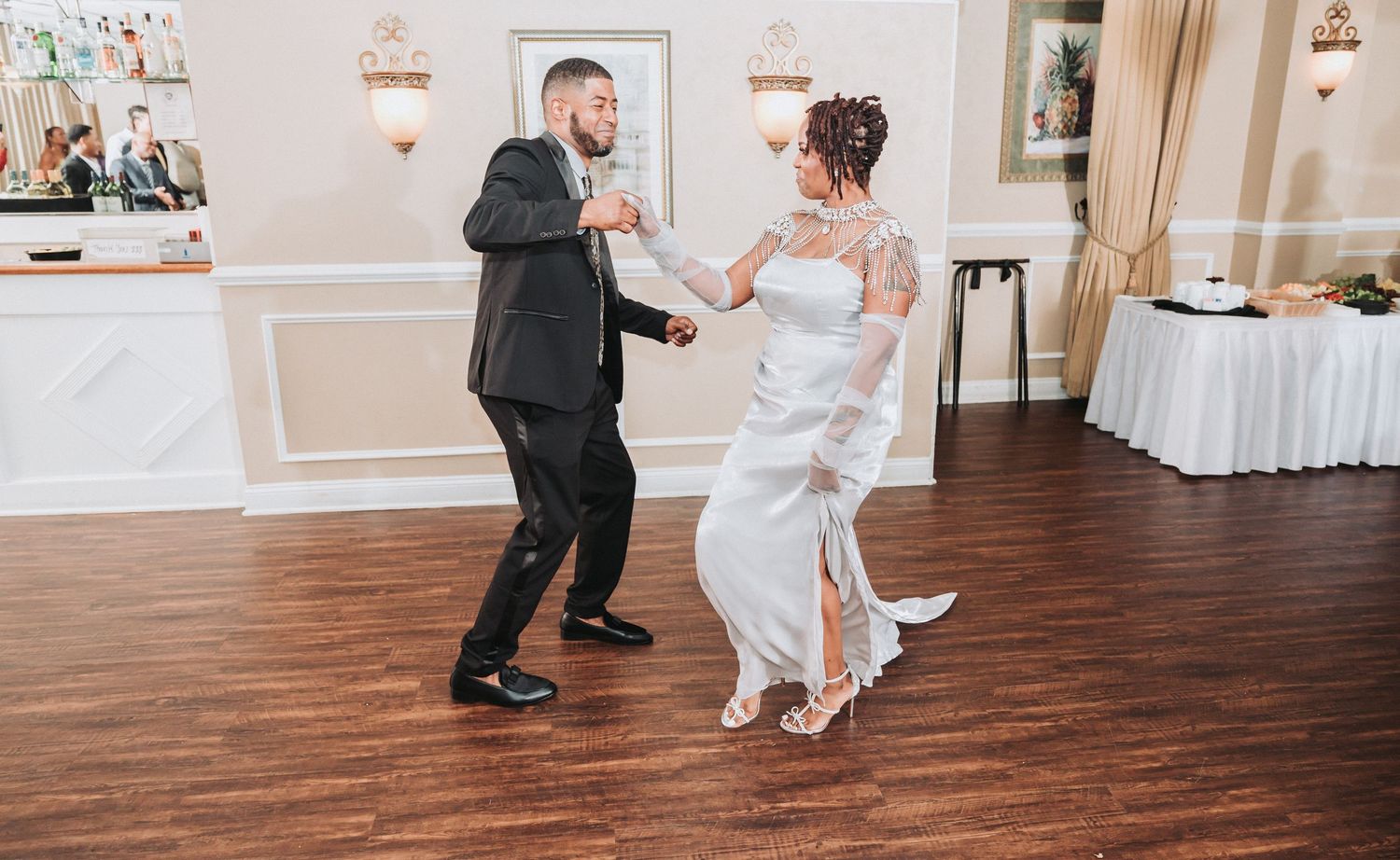Wedding couple dancing together on hardwood floor during their reception celebration.