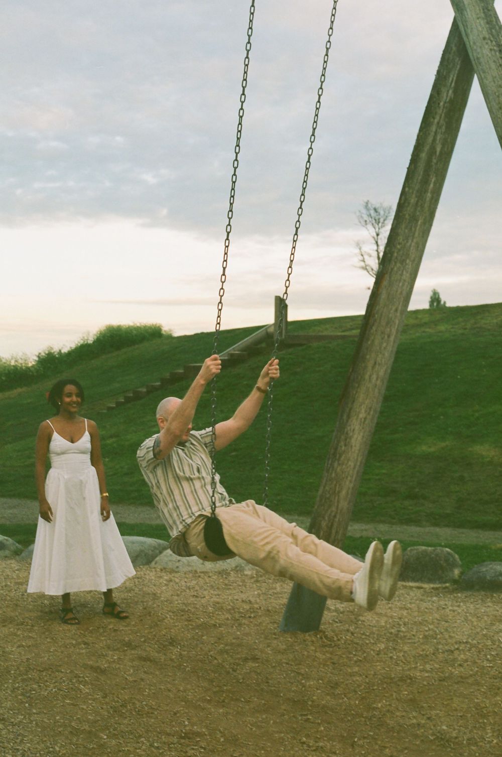 A playful moment at a park with someone swinging while another watches.
