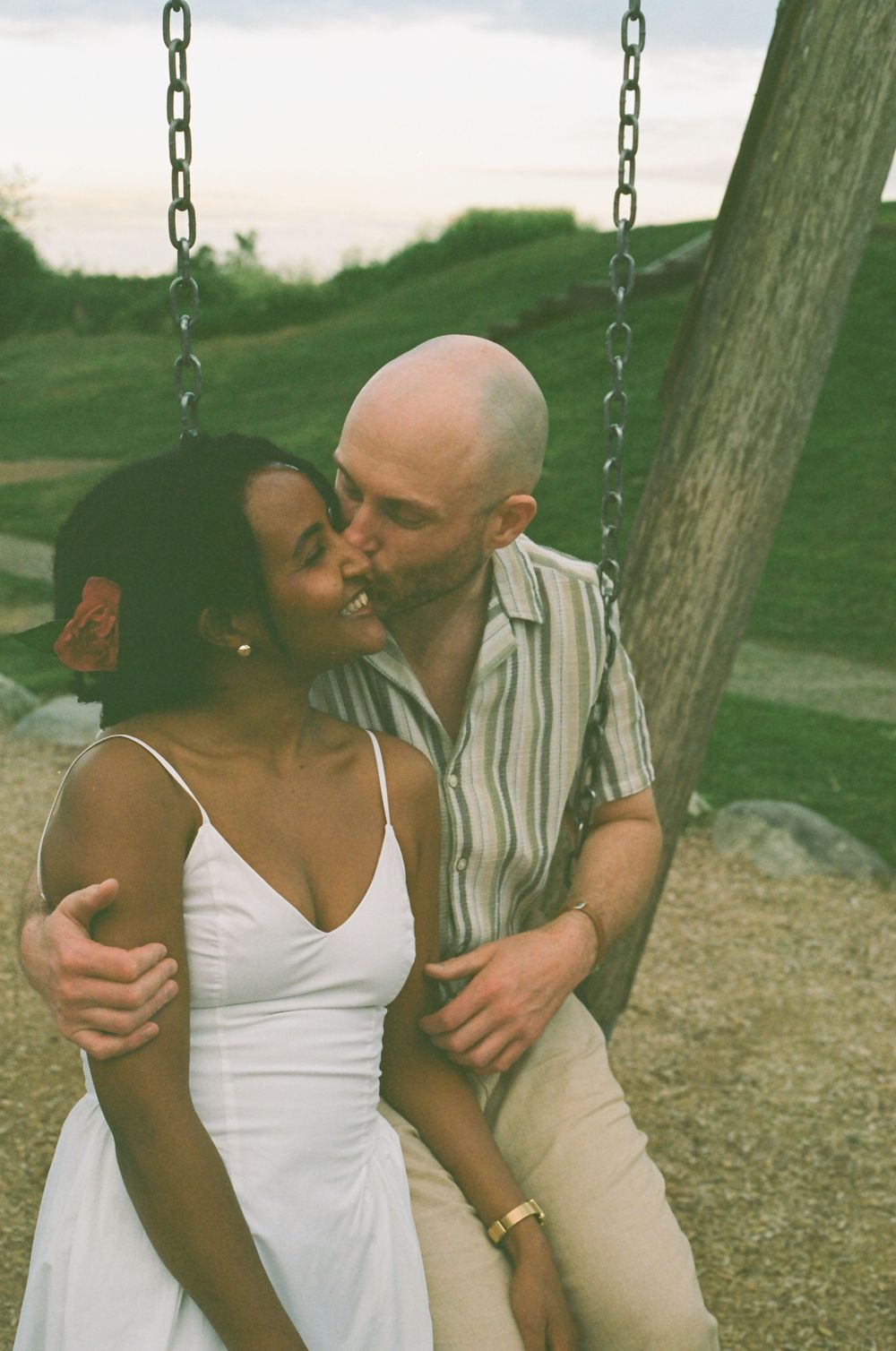 A sweet moment shared between a couple on a swing set at sunset.