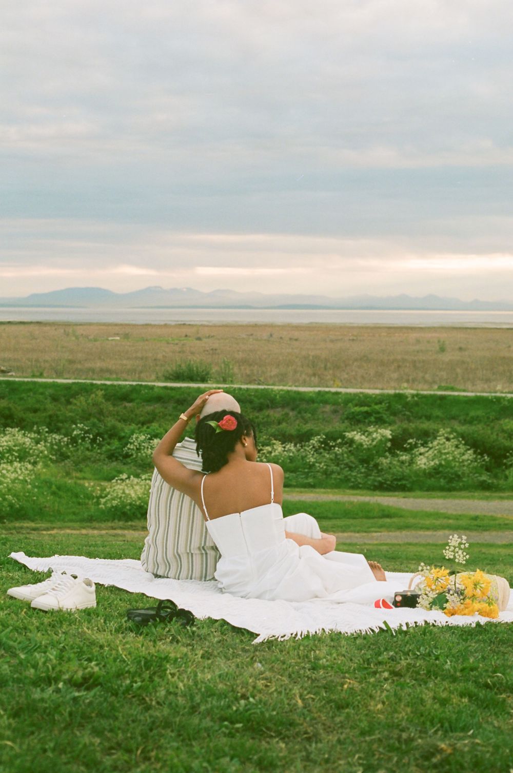 A couple enjoying a peaceful moment on a picnic blanket overlooking a vast landscape.