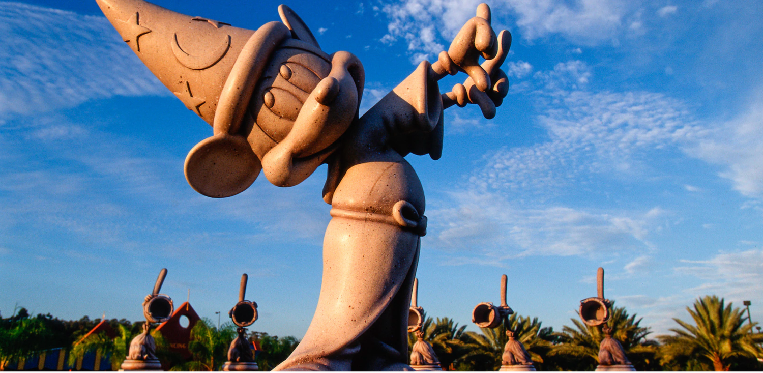 Multiple raised hands against a bright blue sky with palm trees in the background.