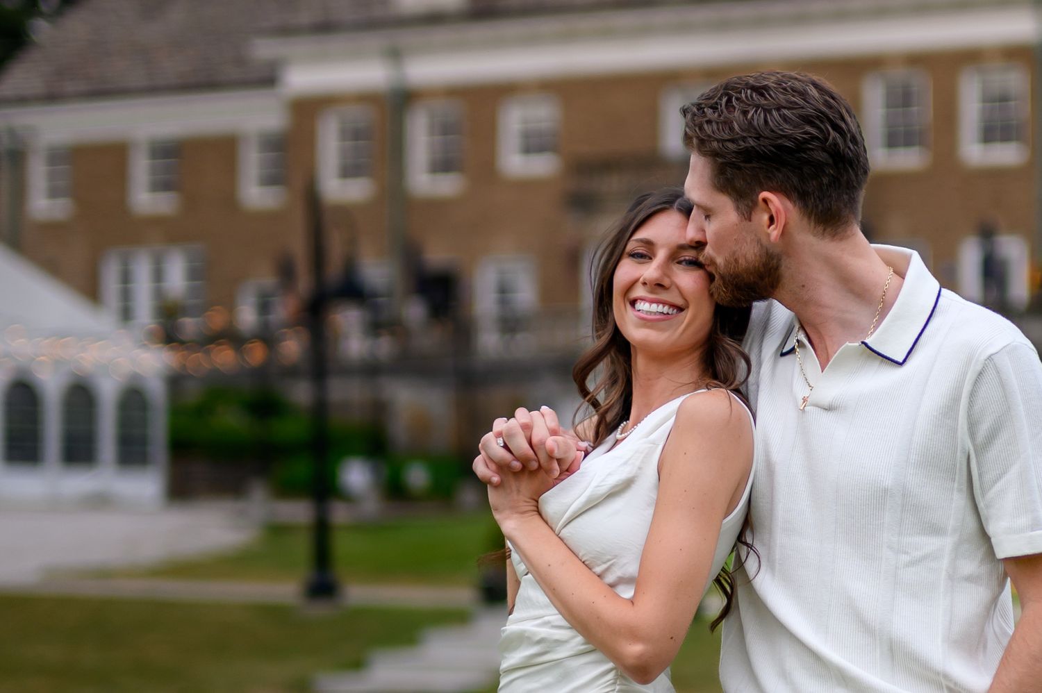 A loving couple dressed in white share a joyful romantic moment together on the lawn of The Felt Estate in Holland Michigan
