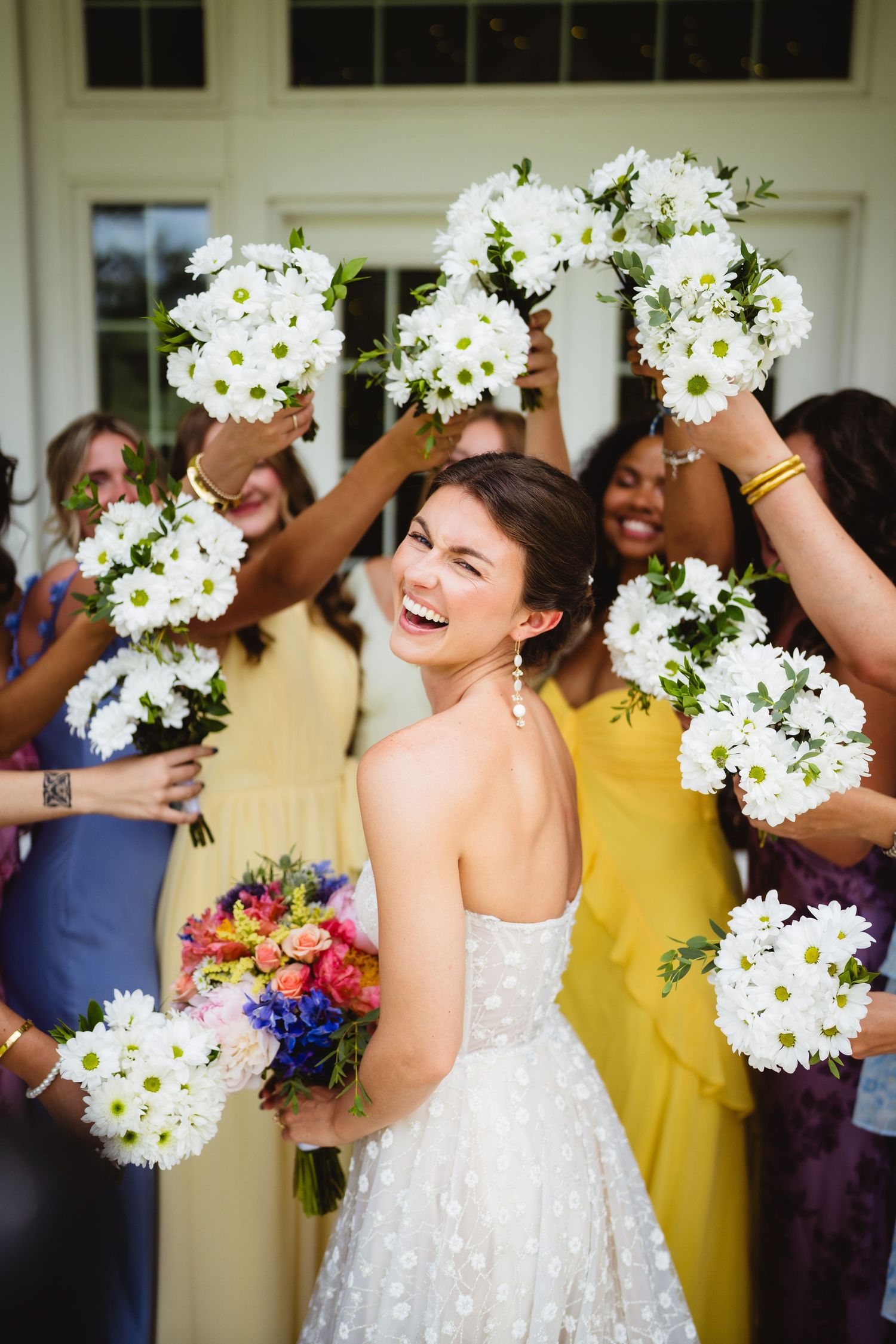Cheerful wedding celebration with guests holding white daisy flower bouquets in an indoor venue.