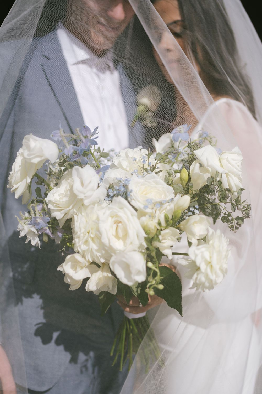 Close-up of elegant white and blue floral wedding bouquet with roses.