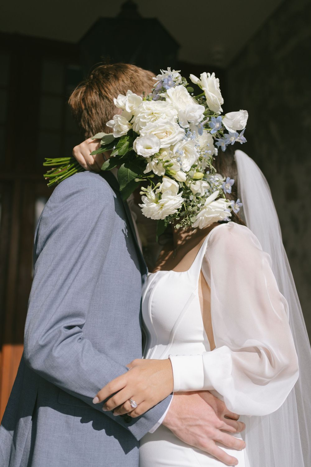 Intimate wedding portraits showing embrace with white floral bouquet details.