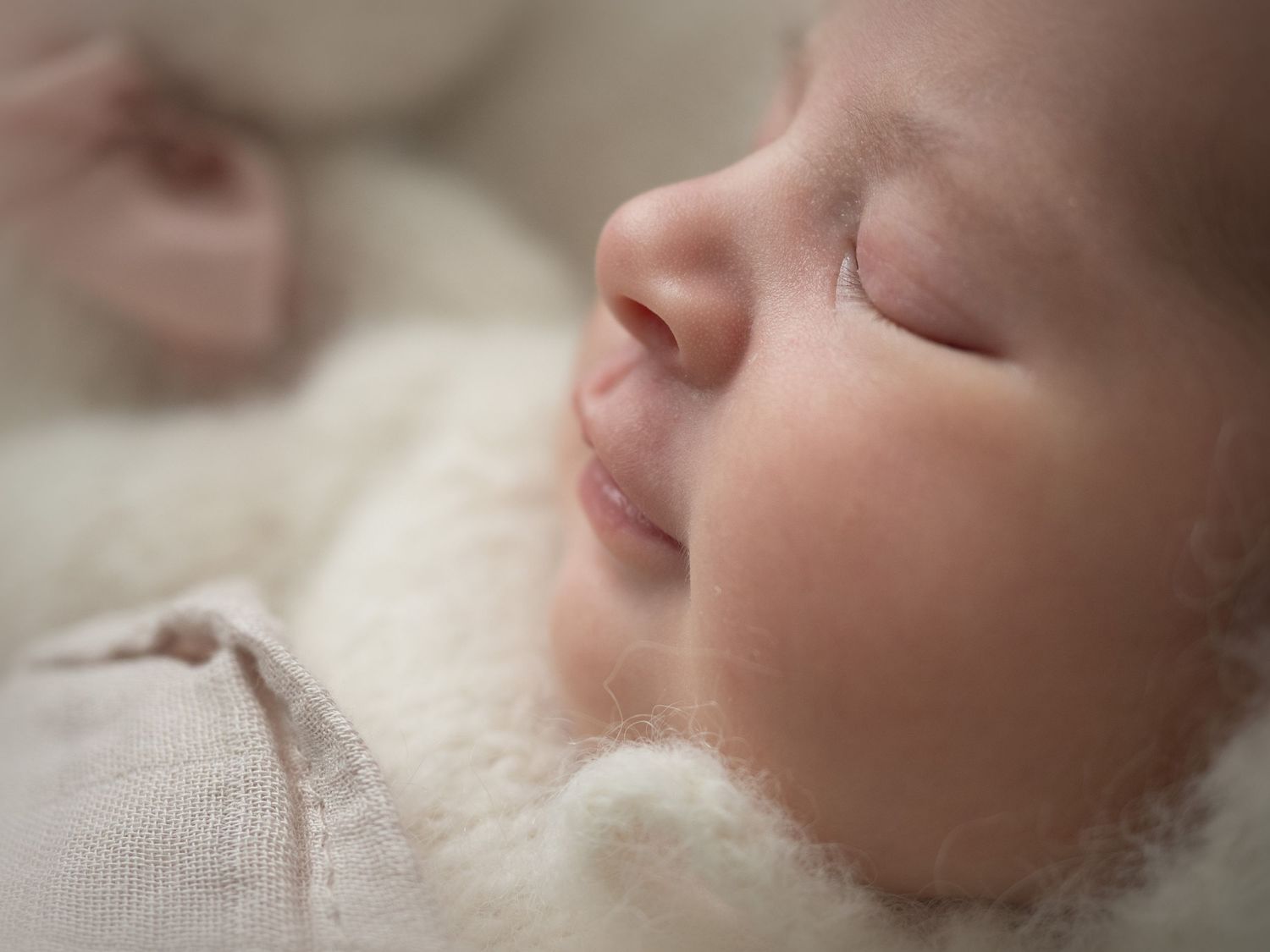Newborn baby girl sleeps peacefully with a little smile, a dreamy, gentle moment full of warmth and love